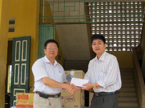 Ông Nguyễn Quốc Long, Trưởng ban Truyền thông, báo Giáo dục Việt Nam (phải) tiếp nhận tiền và quà ủng hộ từ thầy giáo Nguyễn Quang Hiển, Hiệu trưởng Trường THCS Liên Phương